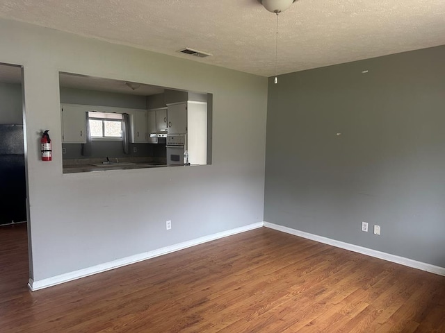 interior space featuring a textured ceiling, wood finished floors, and baseboards