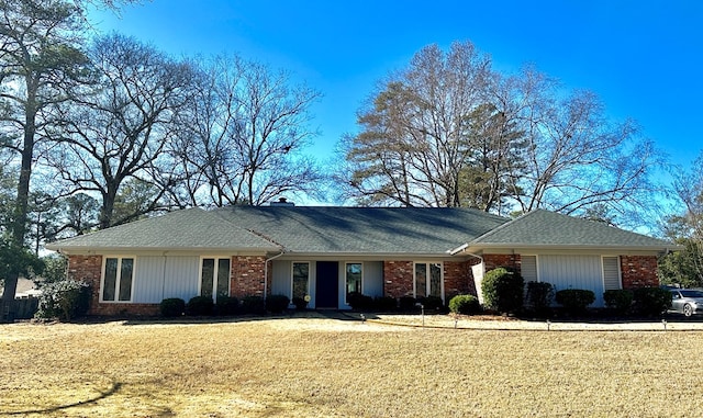 ranch-style home with brick siding, a chimney, and a front yard