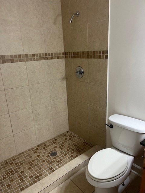 bathroom featuring a tile shower, vanity, and toilet