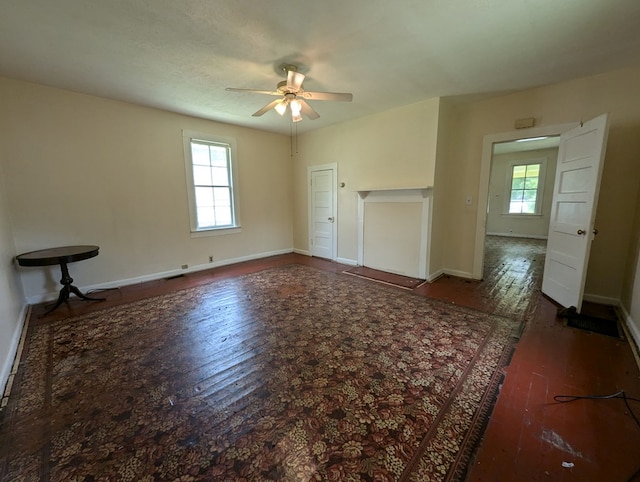 unfurnished living room with ceiling fan and dark wood-type flooring