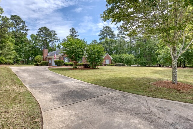 1000 Gramercy Dr, Midland, GA 31820 - view of front facade featuring driveway, a front lawn, a chimney, and an attached garage