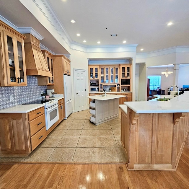 kitchen featuring custom range hood, oven, freestanding refrigerator, a large island with sink, and a sink