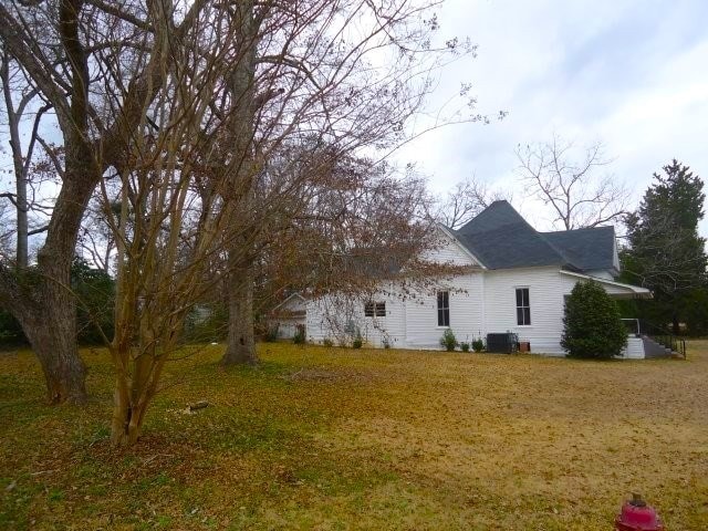 back of house featuring cooling unit and a lawn