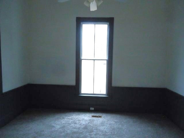 empty room featuring ceiling fan and carpet