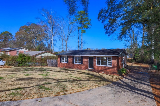 ranch-style house with driveway, fence, a front lawn, and brick siding