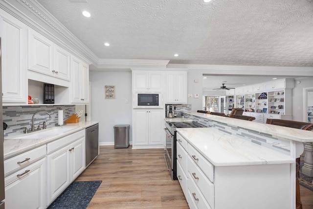 566 Longview Dr, Hamilton, GA 31811 - kitchen featuring a sink, appliances with stainless steel finishes, a peninsula, a breakfast bar area, and ornamental molding