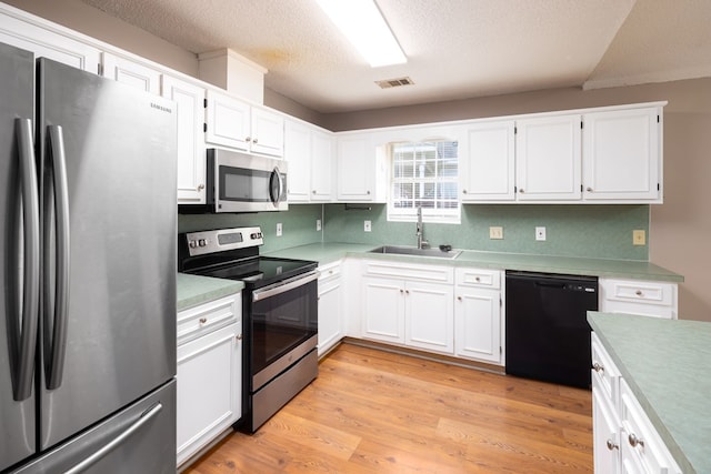 232 Mill Pond Dr, Phenix City, AL 36870 - kitchen featuring appliances with stainless steel finishes, a sink, white cabinetry, light countertops, and light wood-style flooring
