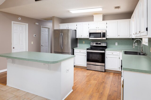 232 Mill Pond Dr, Phenix City, AL 36870 - kitchen with appliances with stainless steel finishes, a sink, white cabinetry, a kitchen island, and light wood-type flooring