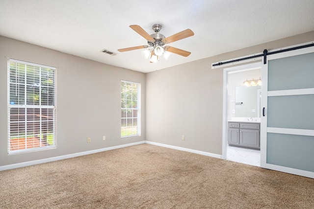 232 Mill Pond Dr, Phenix City, AL 36870 - empty room featuring light carpet, a ceiling fan, a sink, a barn door, and baseboards