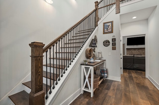 stairway with a towering ceiling and wood-type flooring