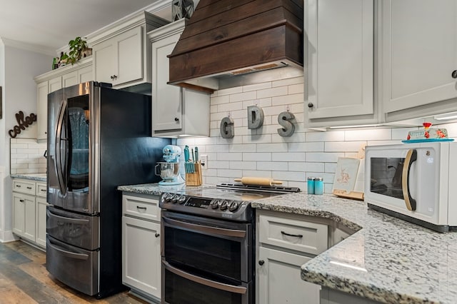 kitchen with crown molding, premium range hood, backsplash, stainless steel appliances, and light stone counters