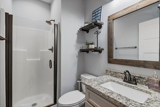 bathroom featuring vanity, toilet, and a shower with door