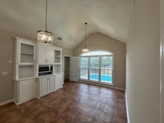 986 Timber Creek Way, Columbus, GA 31904 - kitchen featuring a chandelier, stainless steel microwave, vaulted ceiling, white cabinetry, and glass insert cabinets
