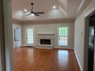 986 Timber Creek Way, Columbus, GA 31904 - unfurnished living room with a tray ceiling, a ceiling fan, ornamental molding, a fireplace with raised hearth, and wood finished floors