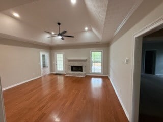 986 Timber Creek Way, Columbus, GA 31904 - unfurnished living room with a raised ceiling, a ceiling fan, a fireplace with raised hearth, wood finished floors, and recessed lighting