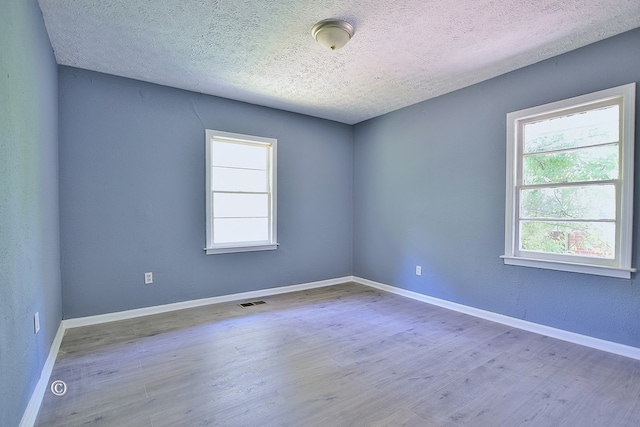 spare room with a textured ceiling and hardwood / wood-style flooring