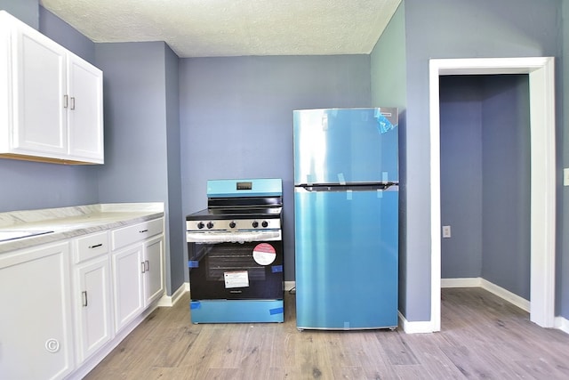 kitchen featuring white cabinetry, stainless steel fridge, stove, and light hardwood / wood-style flooring