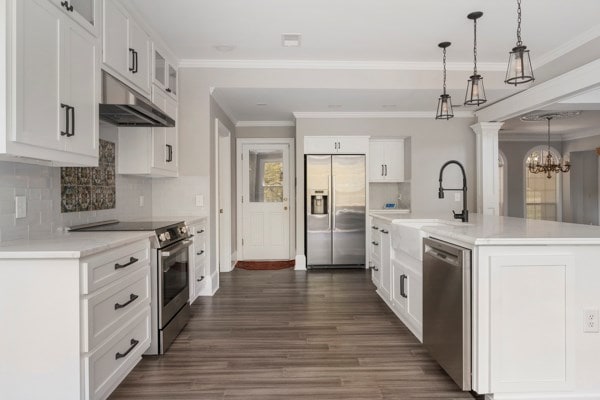 kitchen with white cabinets, decorative light fixtures, stainless steel appliances, and a kitchen island with sink