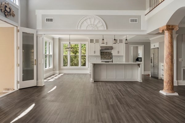 kitchen with dark hardwood / wood-style flooring, decorative columns, pendant lighting, white cabinets, and stainless steel fridge with ice dispenser