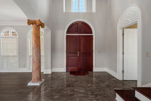 foyer entrance featuring decorative columns, a high ceiling, and ornamental molding