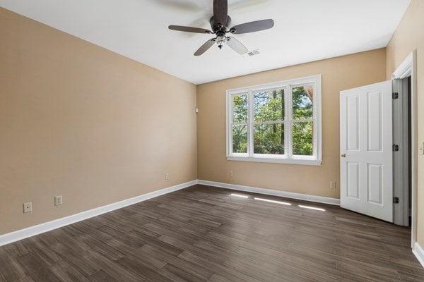 empty room with dark hardwood / wood-style floors and ceiling fan