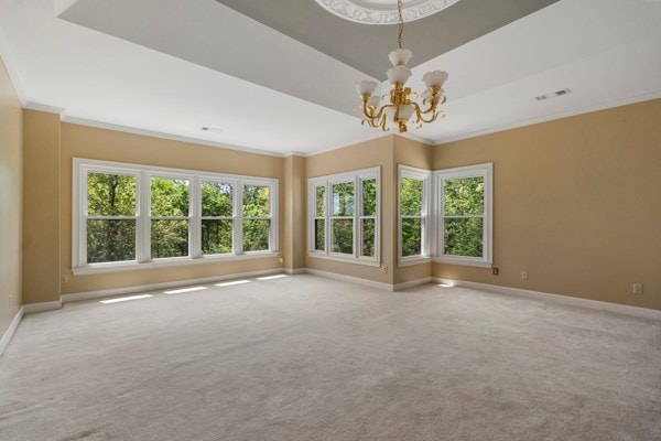 unfurnished room featuring crown molding, plenty of natural light, carpet floors, and a notable chandelier