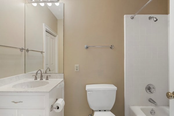 full bathroom featuring vanity, tiled shower / bath, and toilet