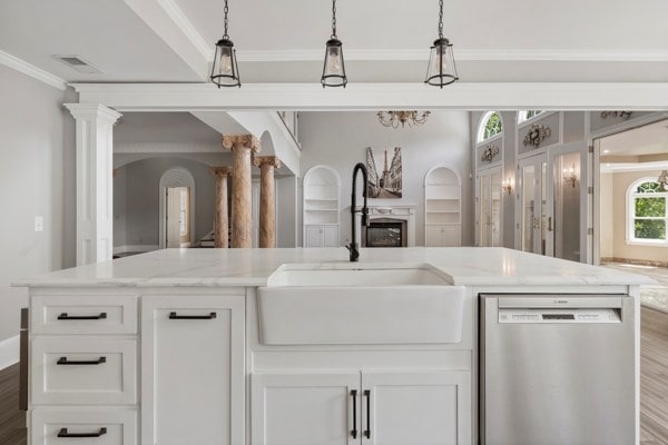 kitchen featuring stainless steel dishwasher, white cabinets, light stone countertops, and sink