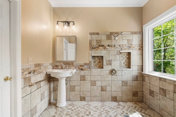 bathroom featuring a tile shower, plenty of natural light, tile walls, and tile patterned flooring