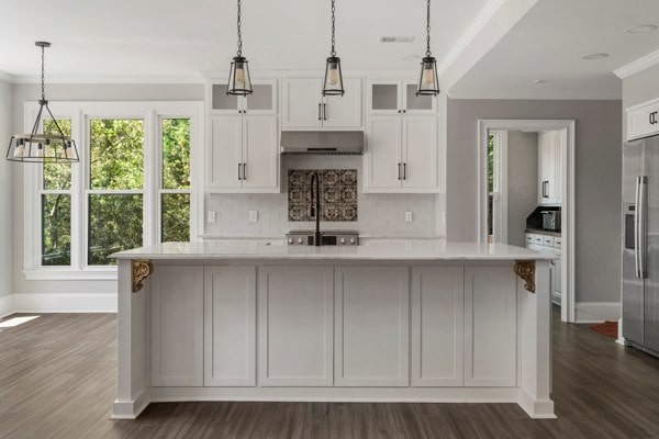 kitchen featuring decorative light fixtures, an island with sink, extractor fan, and stainless steel appliances