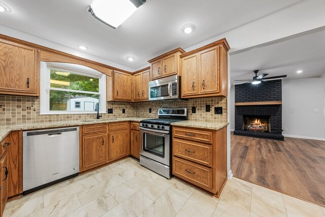 4001 Savannah Dr, Columbus, GA 31907 - kitchen with stainless steel appliances, a ceiling fan, a fireplace, and brown cabinetry