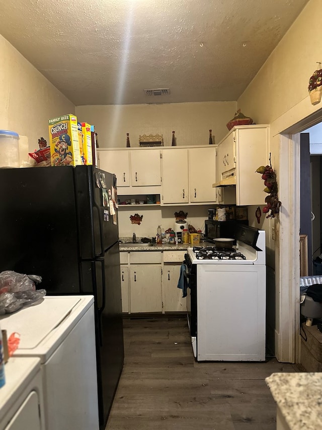 kitchen featuring gas range gas stove, washer and dryer, a textured ceiling, dark hardwood / wood-style flooring, and white cabinets