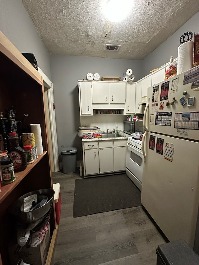 kitchen featuring dark wood-type flooring, sink, a textured ceiling, white appliances, and white cabinets