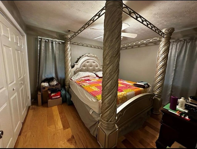 bedroom featuring a textured ceiling, ceiling fan, a closet, and wood finished floors