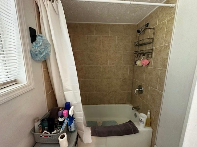 bathroom with a textured ceiling and shower / tub combo with curtain