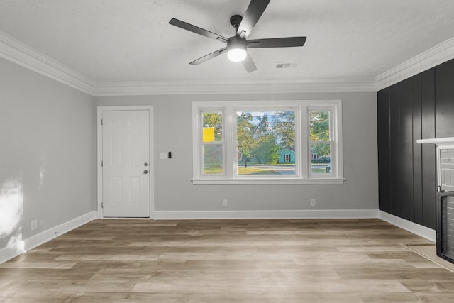 empty room with a textured ceiling, crown molding, and light hardwood / wood-style flooring