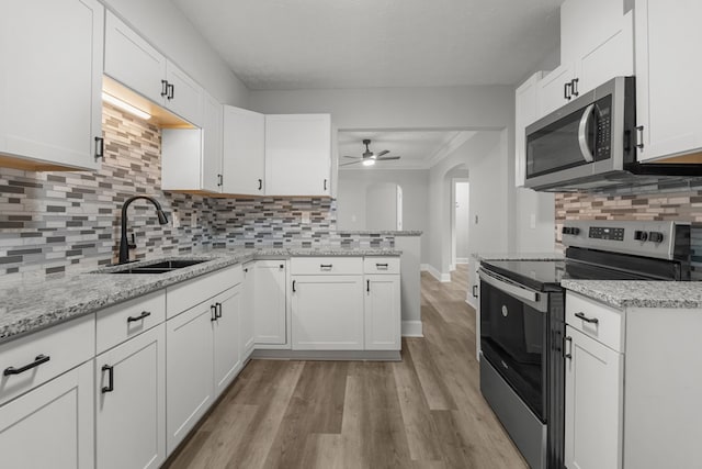 kitchen with backsplash, sink, light hardwood / wood-style flooring, appliances with stainless steel finishes, and white cabinetry