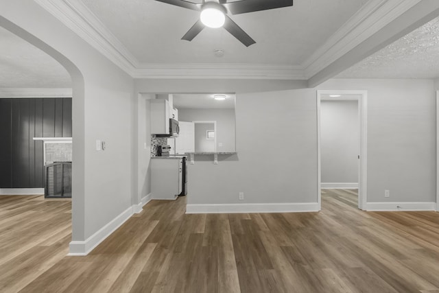 unfurnished living room featuring a brick fireplace, ornamental molding, a textured ceiling, ceiling fan, and hardwood / wood-style flooring