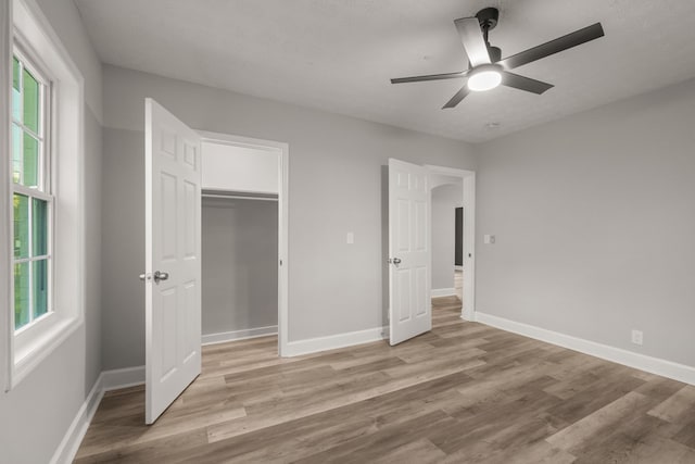 unfurnished bedroom featuring a textured ceiling, a closet, light hardwood / wood-style floors, and ceiling fan