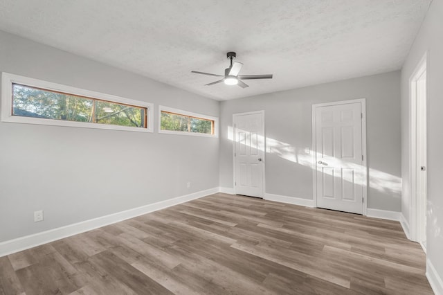 unfurnished bedroom with ceiling fan, a closet, light hardwood / wood-style floors, and a textured ceiling