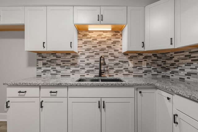 kitchen featuring white cabinets, sink, and tasteful backsplash