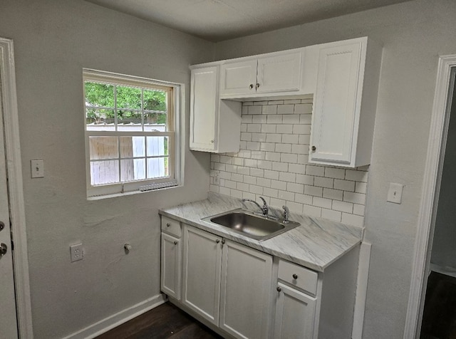 kitchen with white cabinetry, light stone countertops, sink, and decorative backsplash