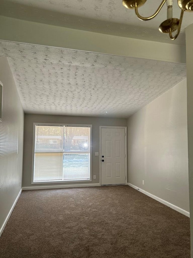 carpeted empty room with a notable chandelier and a textured ceiling