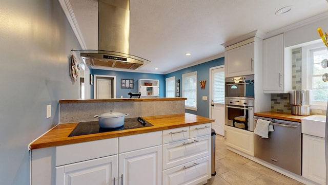 4042 Lyn Dr, Columbus, GA 31909 - kitchen with wooden counters, extractor fan, appliances with stainless steel finishes, ornamental molding, and backsplash