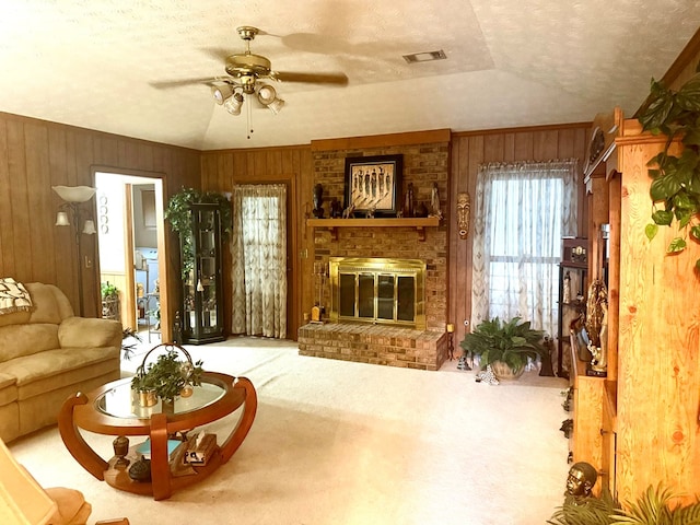 300 Jefferson Dr, Columbus, GA 31907 - living room featuring wood walls, carpet flooring, a ceiling fan, a textured ceiling, and a brick fireplace