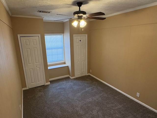 empty room featuring a textured ceiling, a ceiling fan, dark carpet, and crown molding