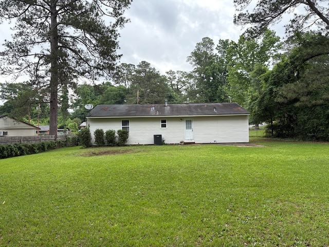 rear view of house with central AC unit and view of wooded area