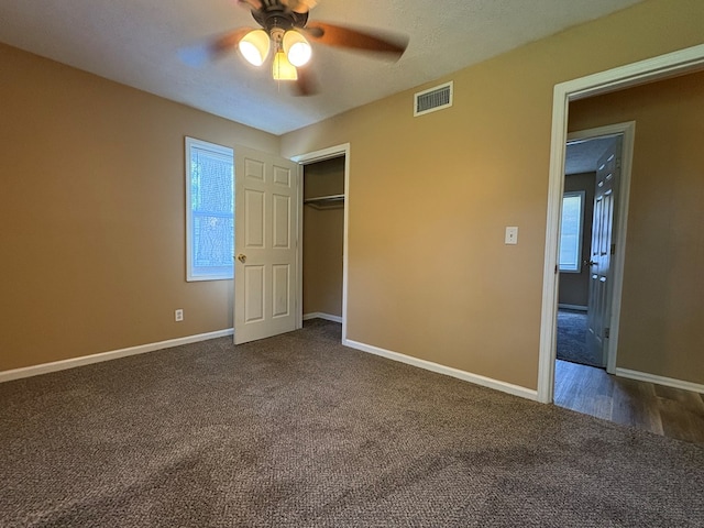 unfurnished bedroom with dark colored carpet, baseboards, a closet, and a ceiling fan