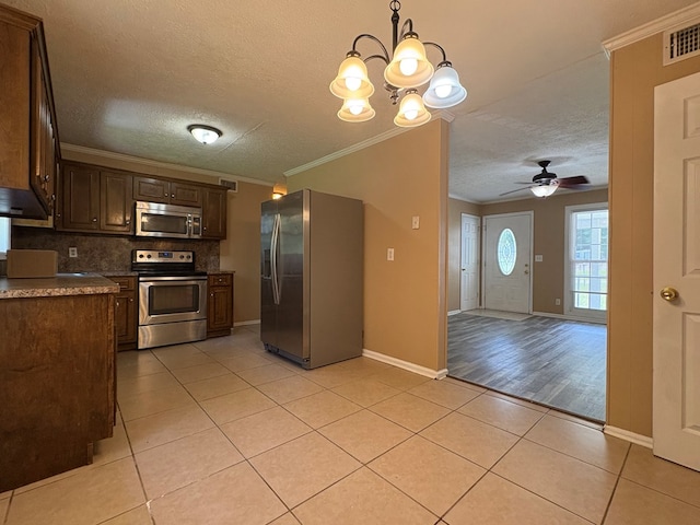 kitchen with stainless steel appliances, light tile patterned floors, a textured ceiling, backsplash, and crown molding