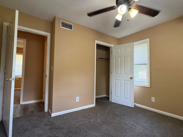 unfurnished bedroom with dark carpet, a closet, ceiling fan, and baseboards